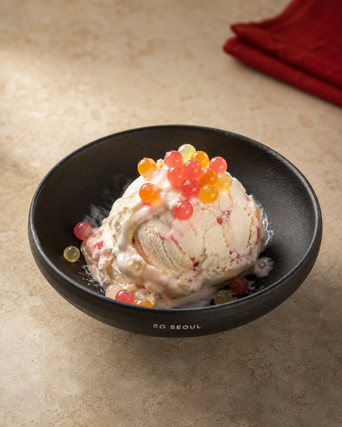 So Seoul ice cream in a black bowl with colourful juice-filled popping boba and natural melting around the edges.
