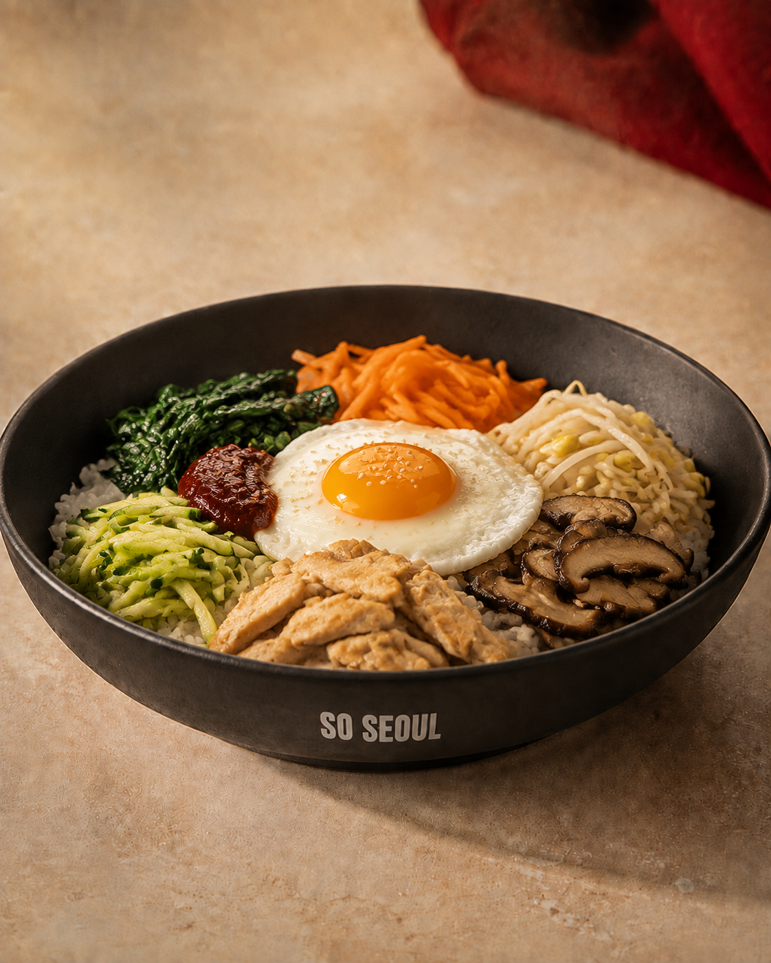 A So Seoul bibimbap bowl with rice, seasoned vegetables, gochujang and a fried egg.